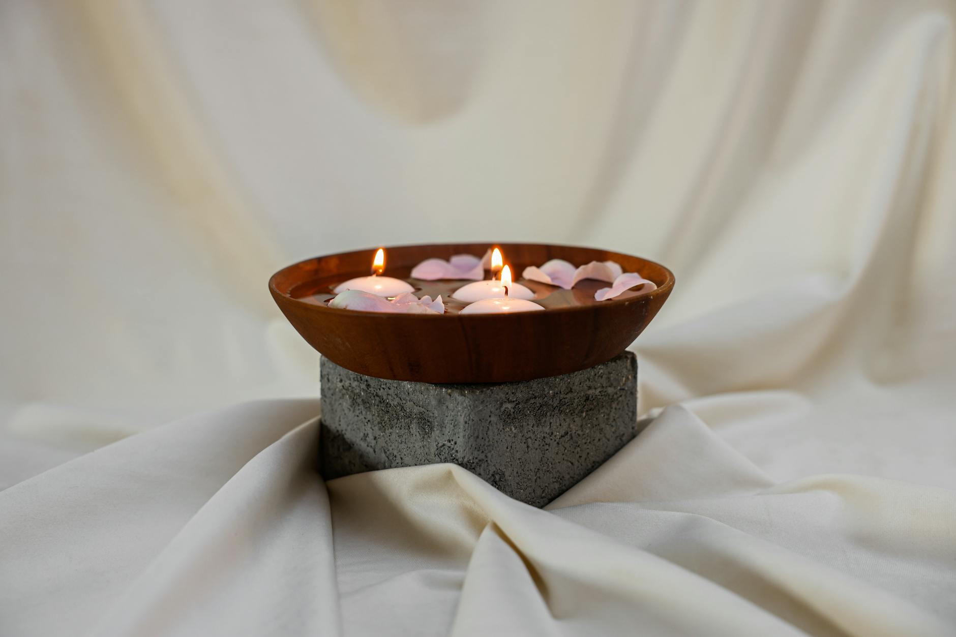 wooden bowl with lighted candles and petals